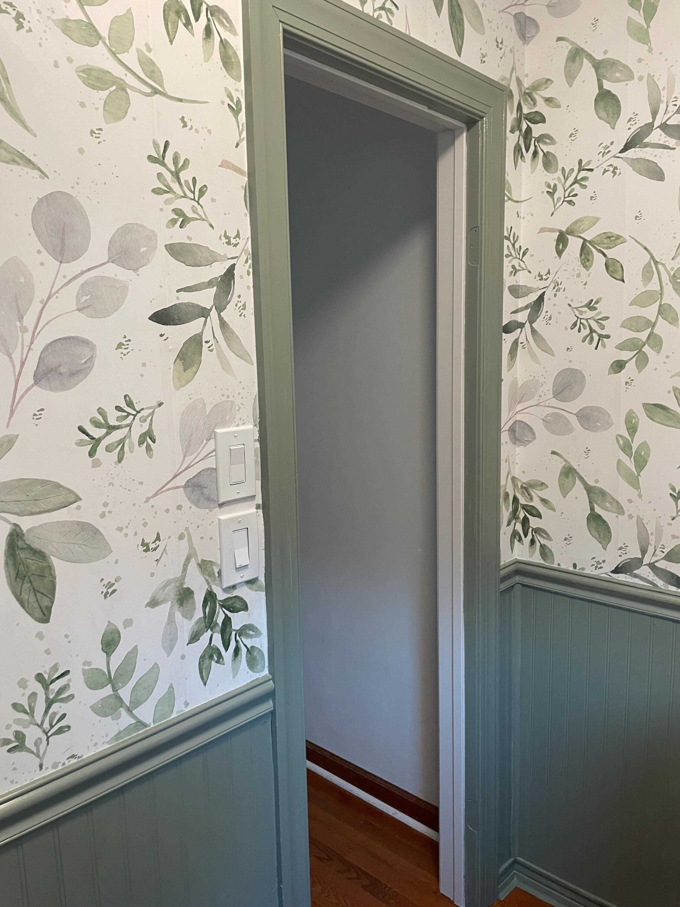 Caroline Greens botanical wallpaper 0160 around a bathroom doorway with sage green trim and wainscoting