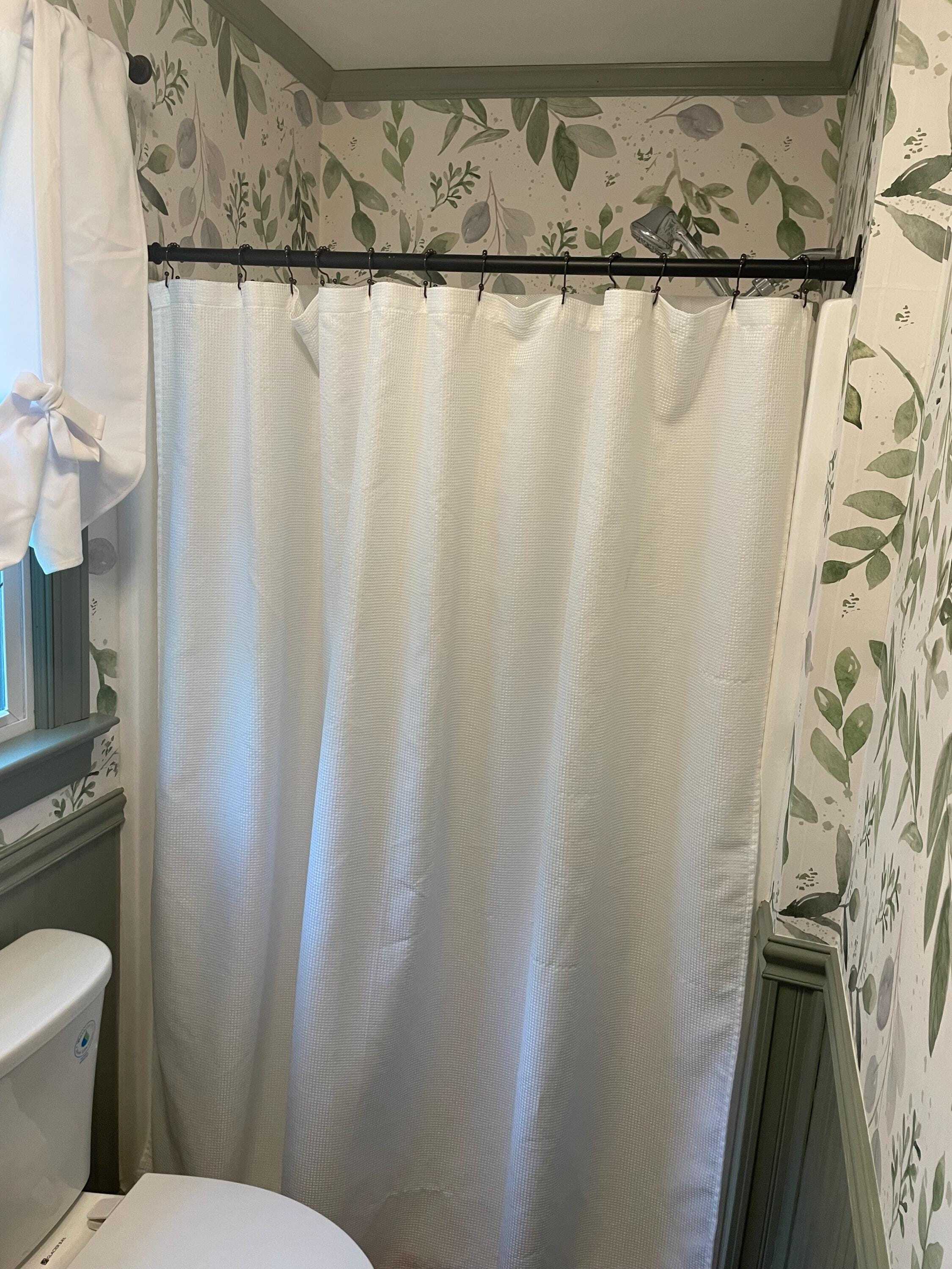 Caroline Greens watercolor foliage wallpaper 0160 surrounding a bathroom shower with sage green trim