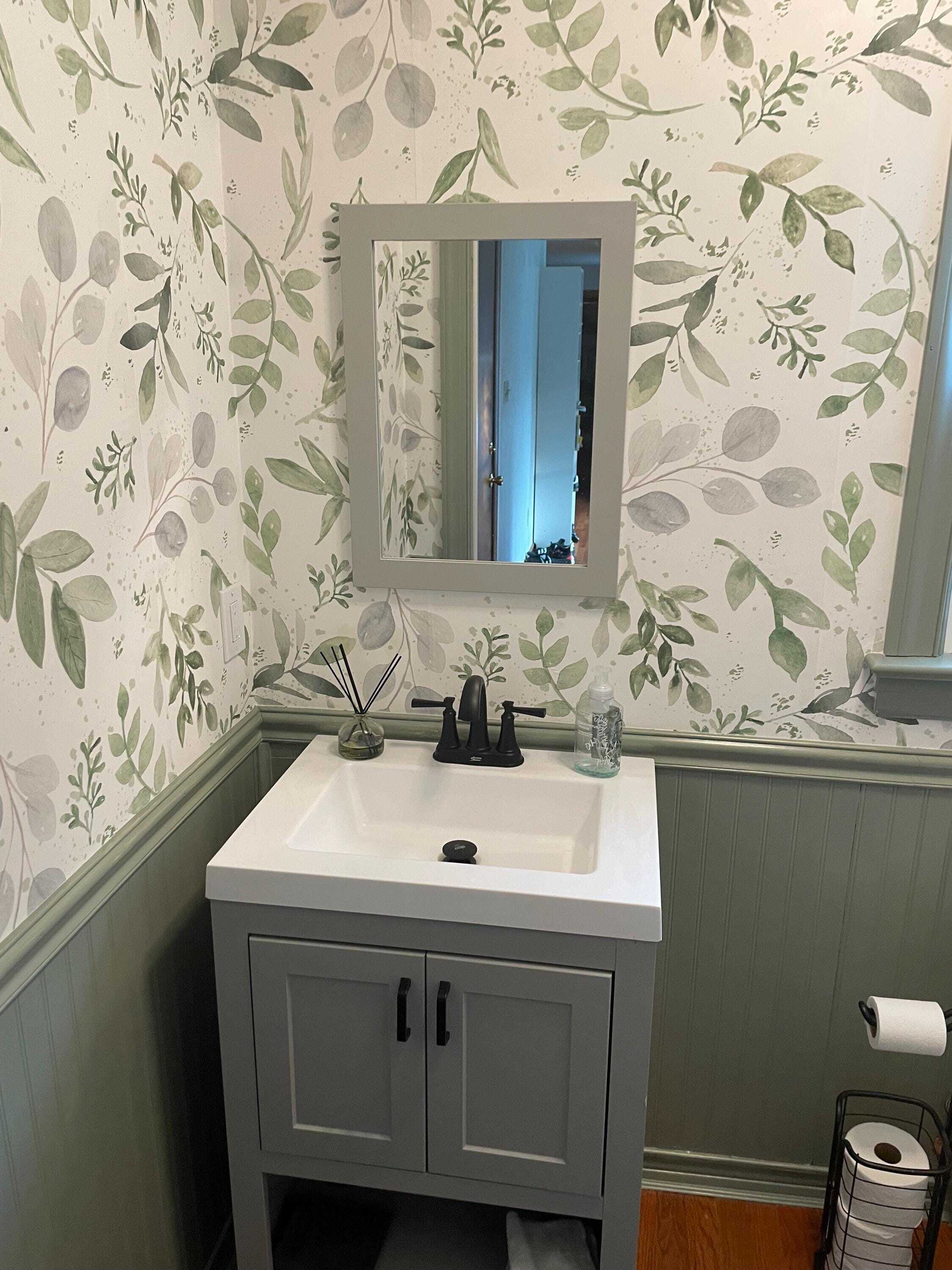 Caroline Greens botanical wallpaper 0160 in a powder room with a grey vanity, green wainscoting and black faucet